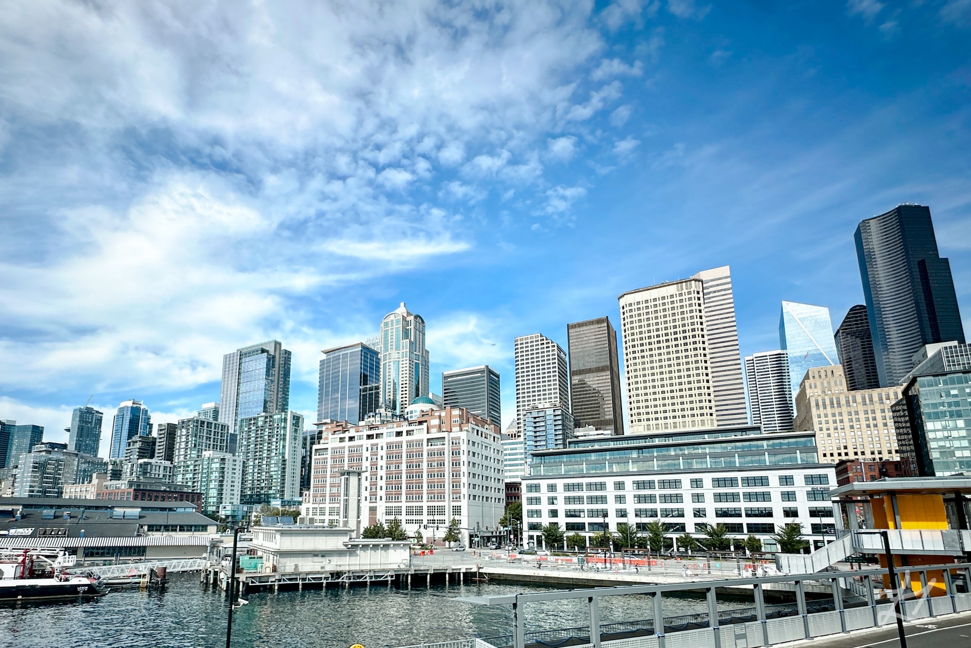 Seattle waterfront with ferries, sailboats, and seafood restaurants along the piers.